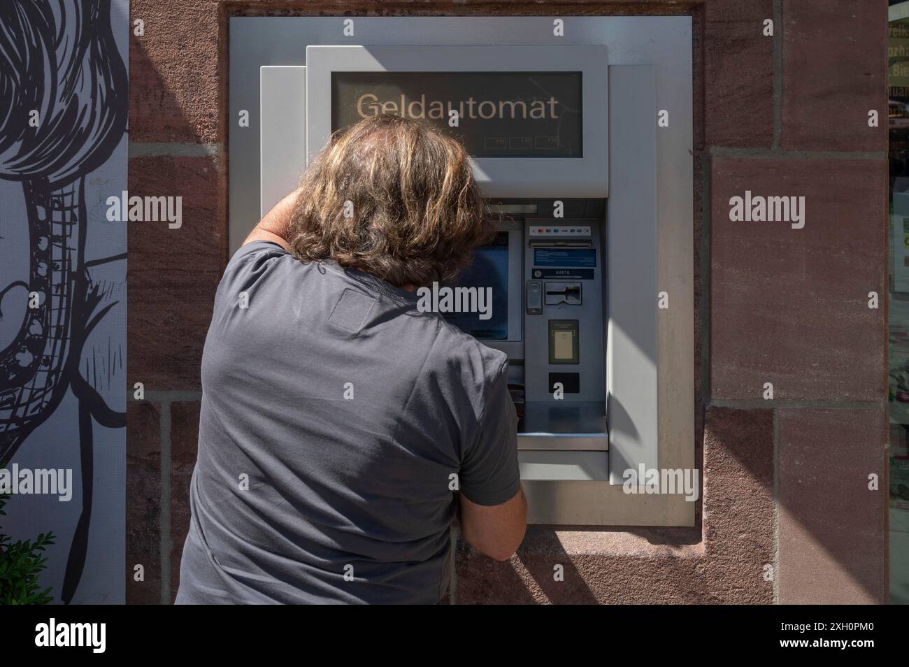 Uomo che ritira denaro da un bancomat, Norimberga, Franconia media, Norimberga, Germania Foto Stock