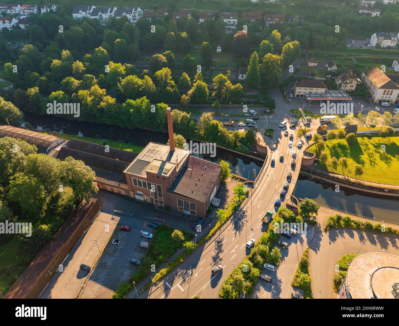 Veduta aerea di un edificio industriale fabbrica di tessuti e soffitti con camino vicino a una strada con auto, vicino a un fiume e circondato da alberi, Calw Foto Stock