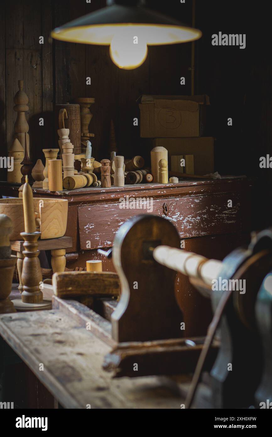 Questa suggestiva fotografia cattura l'essenza di un'accogliente officina di lavorazione del legno piena di vari strumenti e pezzi di legno lavorati in modo complesso. L'amb Foto Stock