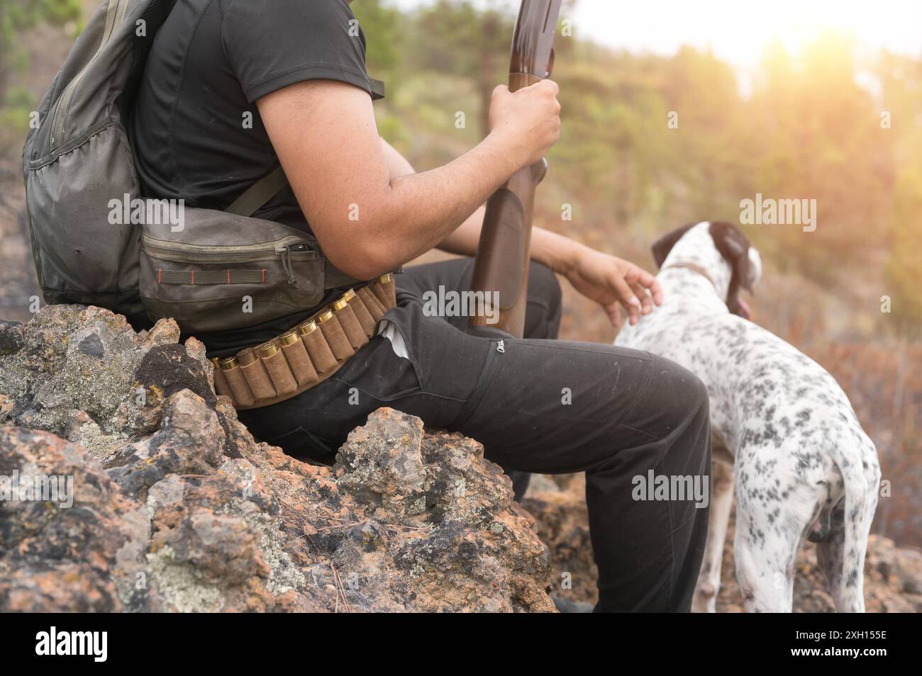 Vista ravvicinata di un cacciatore irriconoscibile e del suo cane nella foresta. Foto di alta qualità Foto Stock