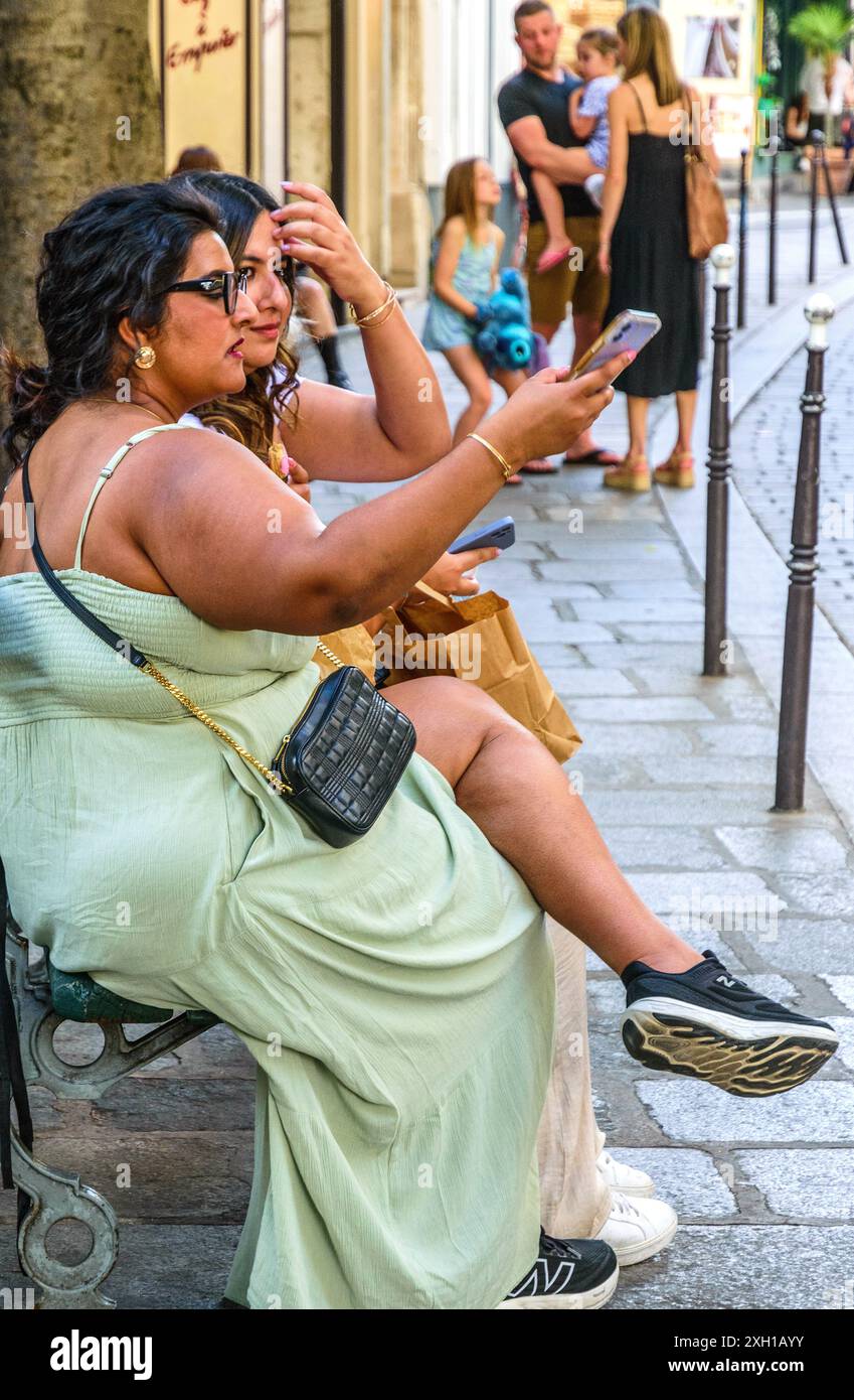 Plus-size Woman and Friend seduto e in possesso di smartphone (per selfie?), Parigi 75004, Francia. Foto Stock