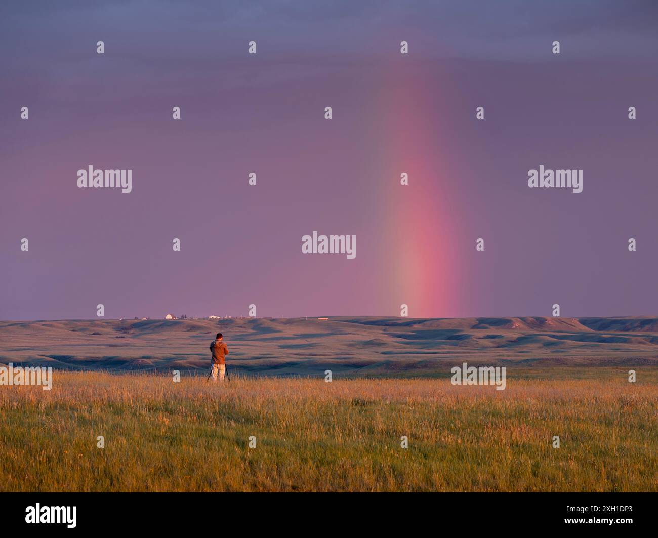 Un uomo non identificabile fotografa un arcobaleno serale nel Grasslands National Park, Saskatchewan, Canada Foto Stock