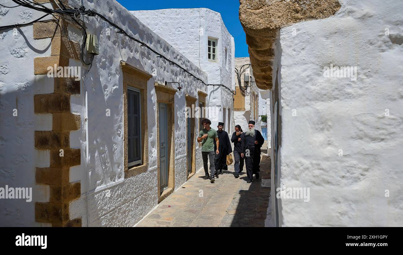 Gruppo di persone che camminano attraverso uno stretto vicolo con edifici bianchi, giorno di sole, Chora, la città principale Patmos, Patmos, città vecchia, Dodecaneso, isole greche Foto Stock