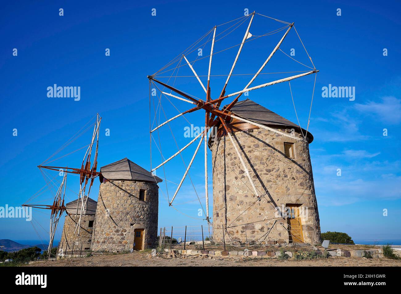 Due vecchi mulini a vento sotto un cielo azzurro e un paesaggio naturale, mulini a vento, su un crinale, sopra Chora, la città principale di Patmos, Patmos, centro storico, Dodecaneso Foto Stock