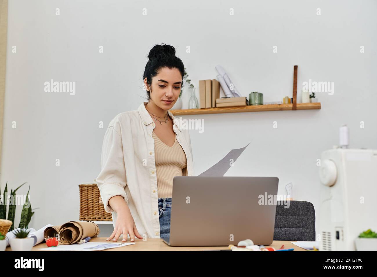 Giovane donna con un abbigliamento casual, indossa abiti da upcycling su un notebook per una moda eco-consapevole. Foto Stock