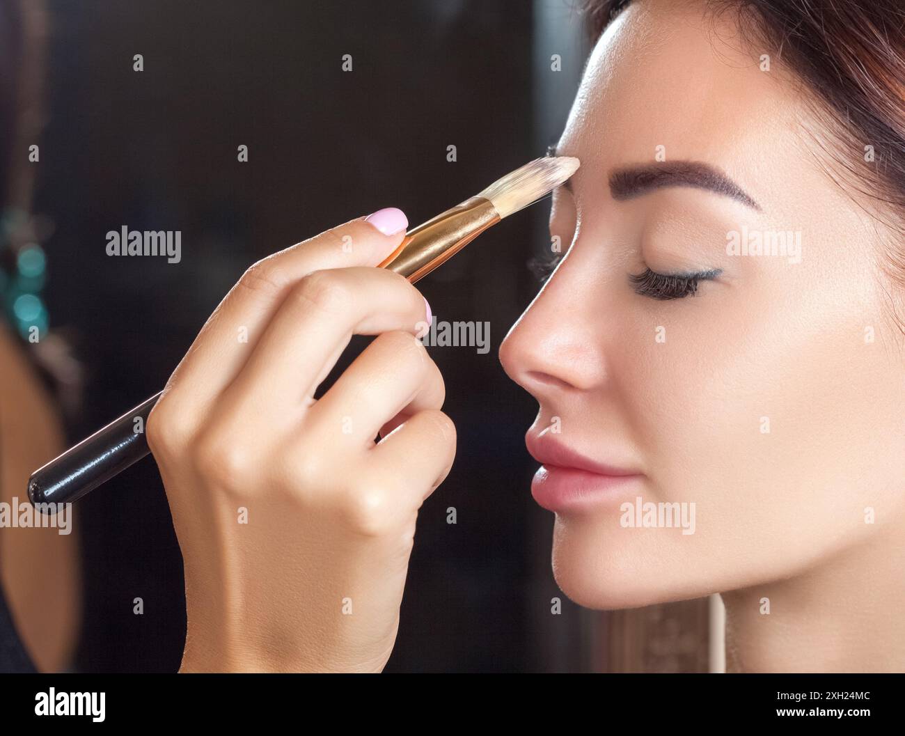 Ritratto di una bella donna felice con la pelle pulita in un salone di bellezza. L'artista di trucco le fa il trucco. Trucco professionale e cosmetologia pelle auto Foto Stock