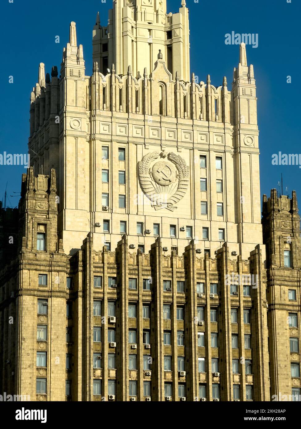 Vista ravvicinata di un grattacielo storico ornato con emblema di rilievo sotto la luce del sole e il cielo azzurro. Foto Stock