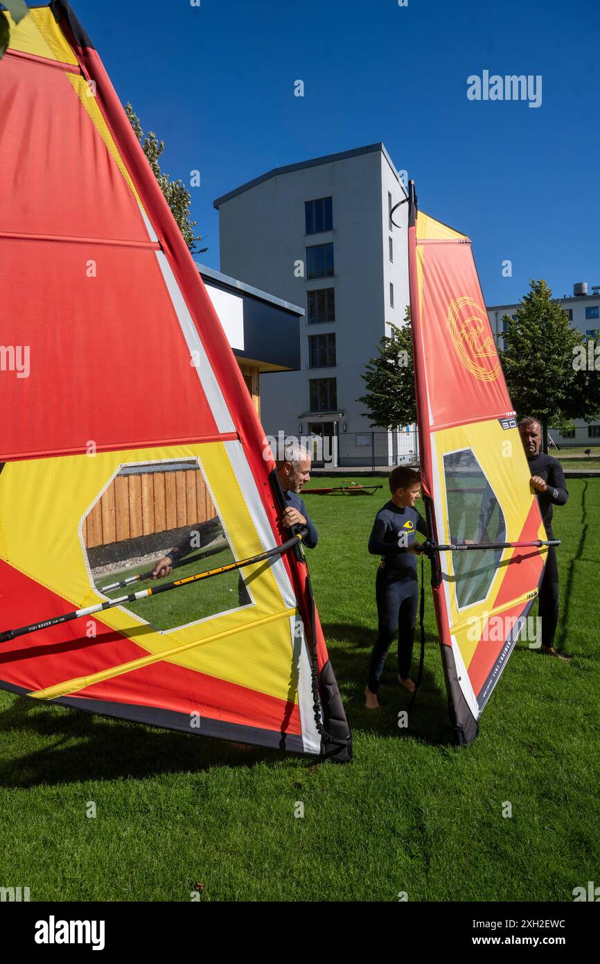 Prora, Germania. 11 luglio 2024. Gli studenti della scuola di vela Binz sono consigliati da Jan Quinnert (r), istruttore di windsurf presso la scuola di surf Prora. Il più grande ostello della gioventù del Meclemburgo-Vorpommern a Prora ha aggiunto una scuola di surf alla sua gamma di servizi. La Binz Sailing School, fornitore della scuola di surf di Prora, offre ora corsi di windsurf e stand-up paddling, nonché tour guidati in kayak. Crediti: Stefan Sauer/dpa/ZB/dpa/Alamy Live News Foto Stock