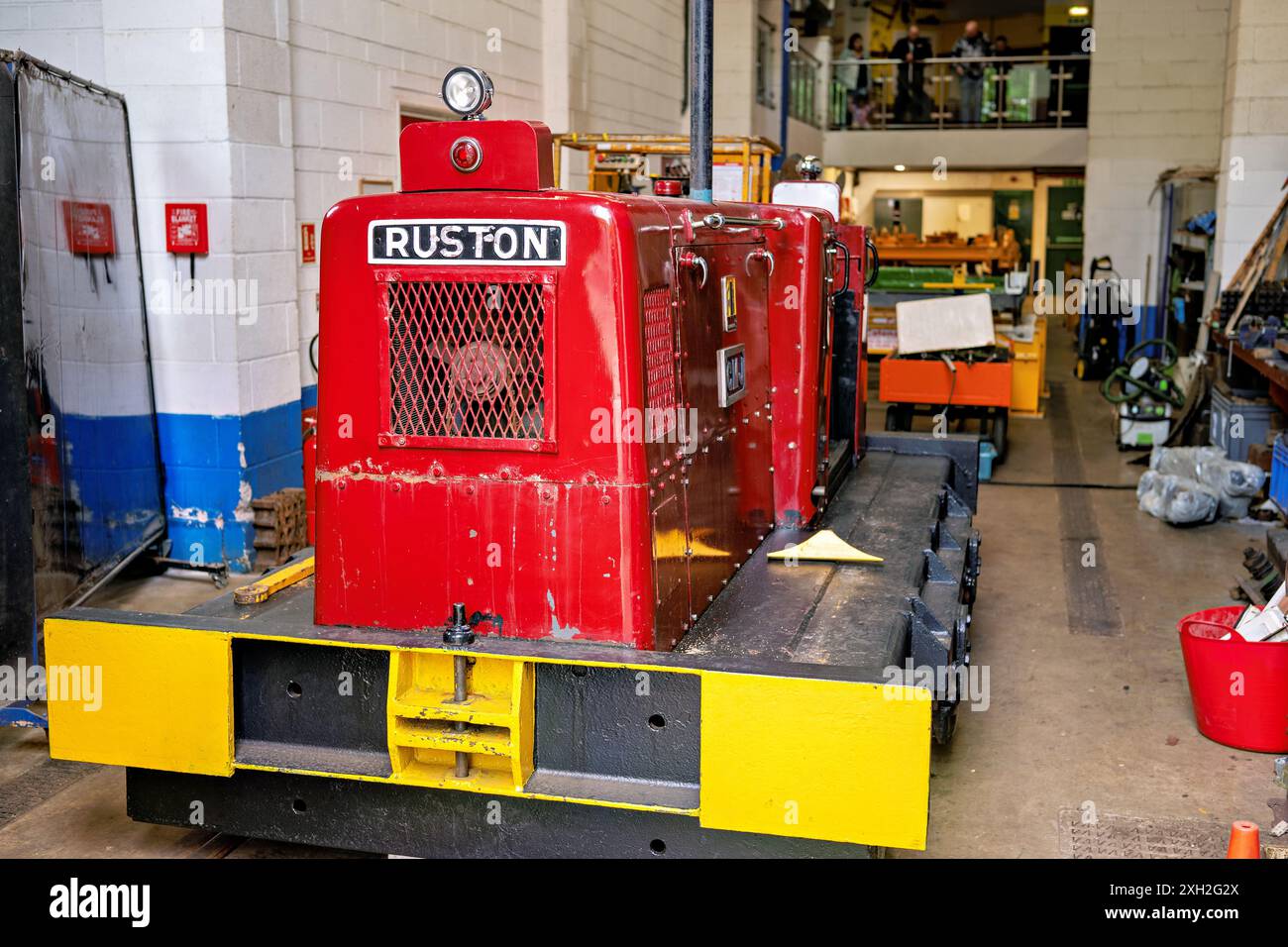 Locomotiva industriale rossa d'epoca all'interno di una spaziosa officina con vari strumenti e attrezzature. Crich Regno Unito. Foto Stock