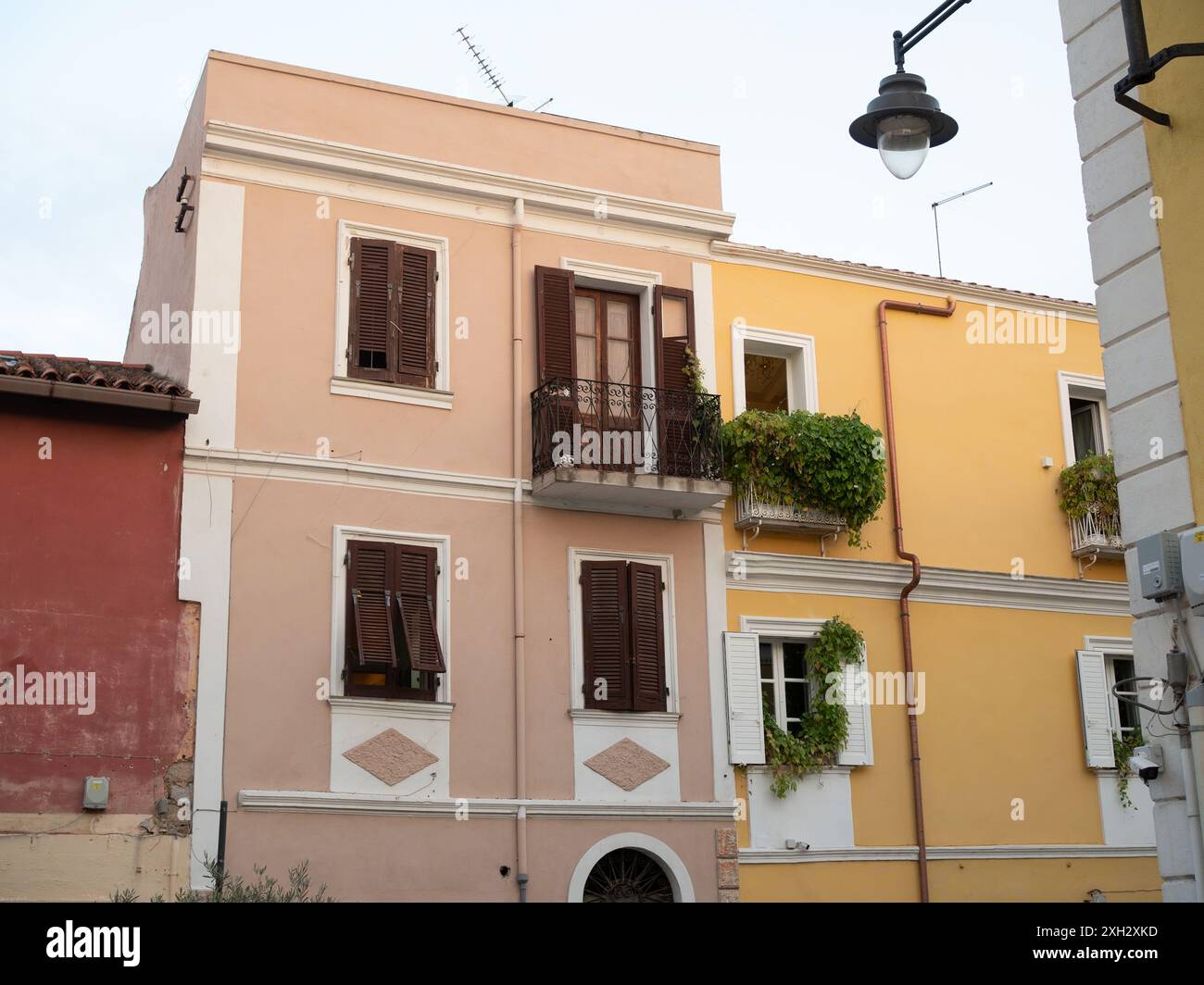 Città vecchia di Olbia: Uno scatto orizzontale di case italiane a due piani in tre colori: Terracotta, rosa pastello e giallo vibrante. Foto Stock