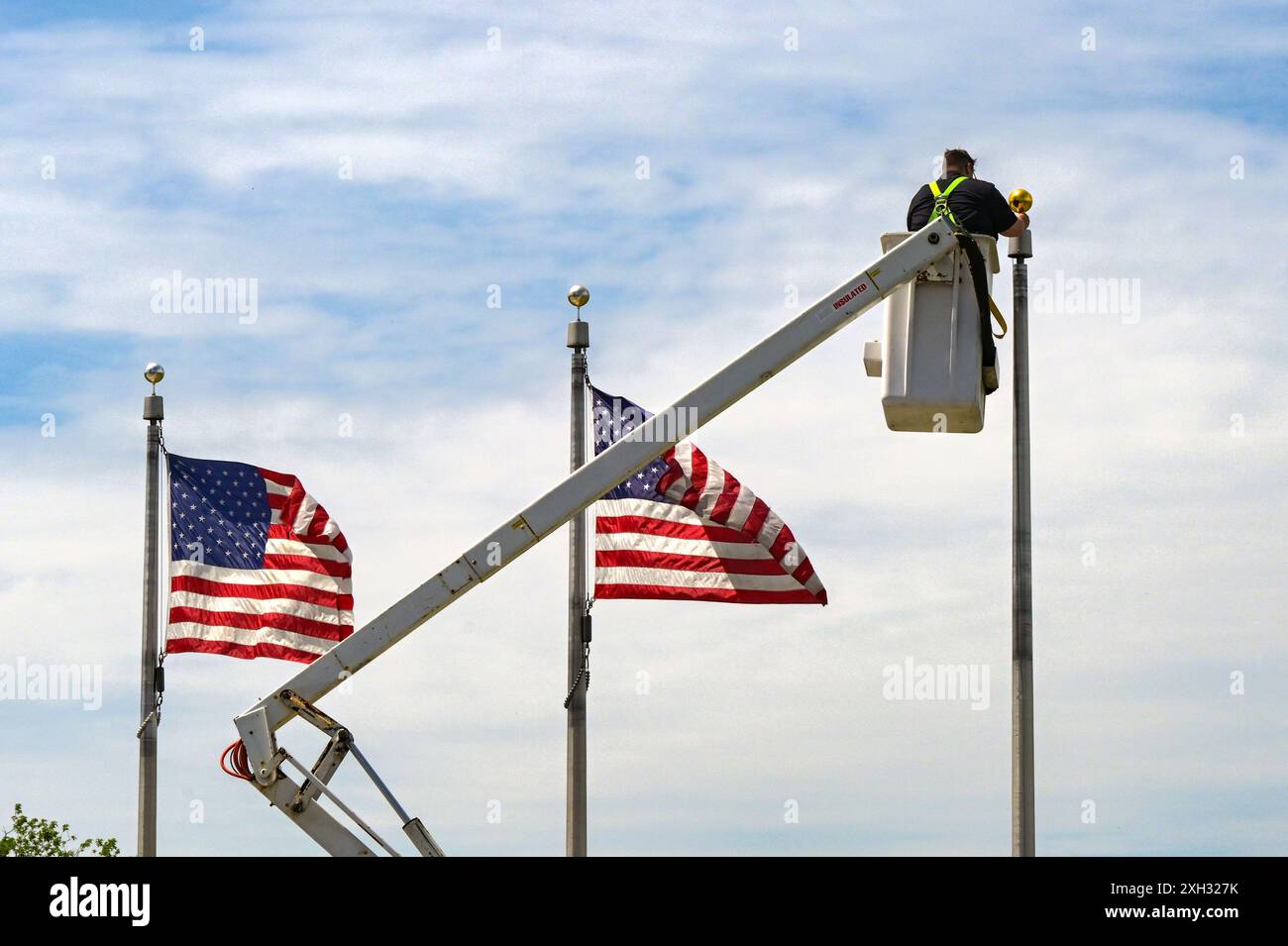 Washington DC, USA - 30 aprile 2024: Addetto alla manutenzione su una piattaforma idraulica che fissa una bandiera su un palo al Washington Monument a Washington DC Foto Stock