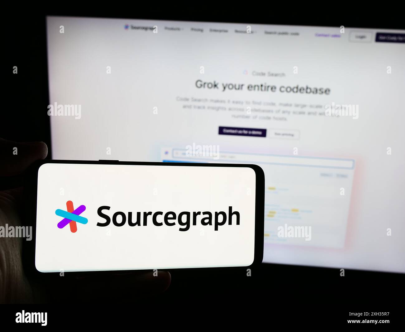 Persona che detiene lo smartphone con il logo della società statunitense di intelligence in codice Sourcegraph Inc. Davanti al sito Web. Mettere a fuoco il display del telefono. Foto Stock
