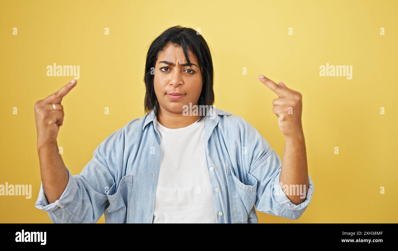 Donna ispanica di mezza età che gestiva su sfondo giallo Foto Stock