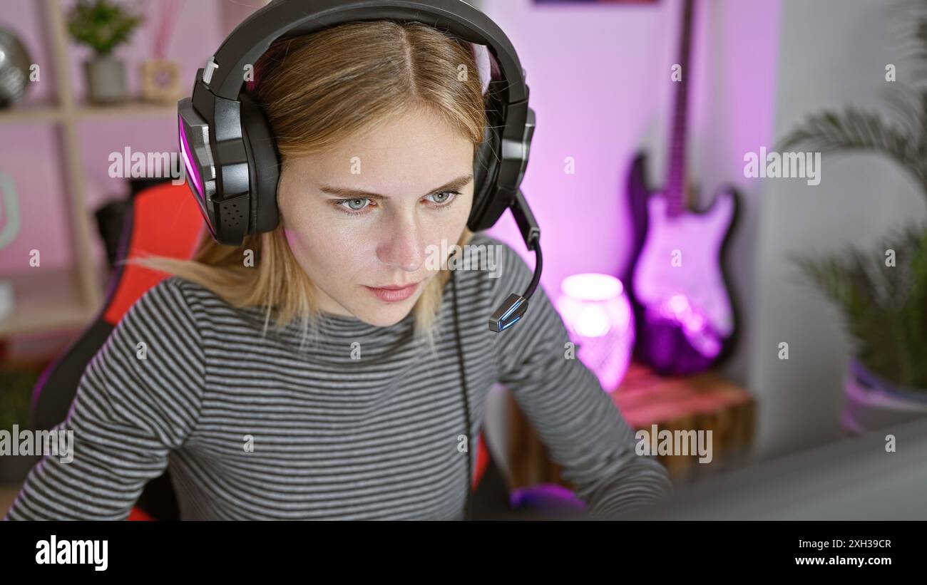 Donna bionda con cuffie che gioca in una stanza colorata di notte Foto Stock