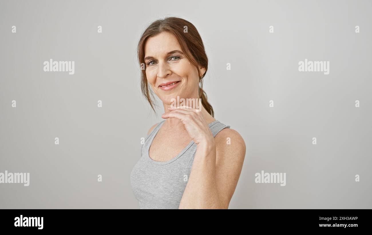 Una donna di mezza età sicura con i capelli corti si posa in un top senza maniche su uno sfondo bianco. Foto Stock