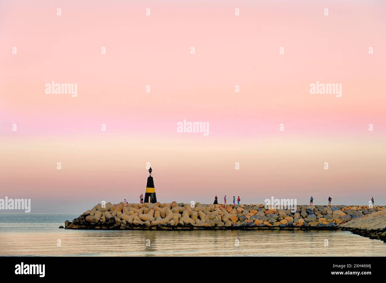 Passeggiata serale lungo il faro al tramonto sul porticciolo di Benalmadena in Spagna Foto Stock