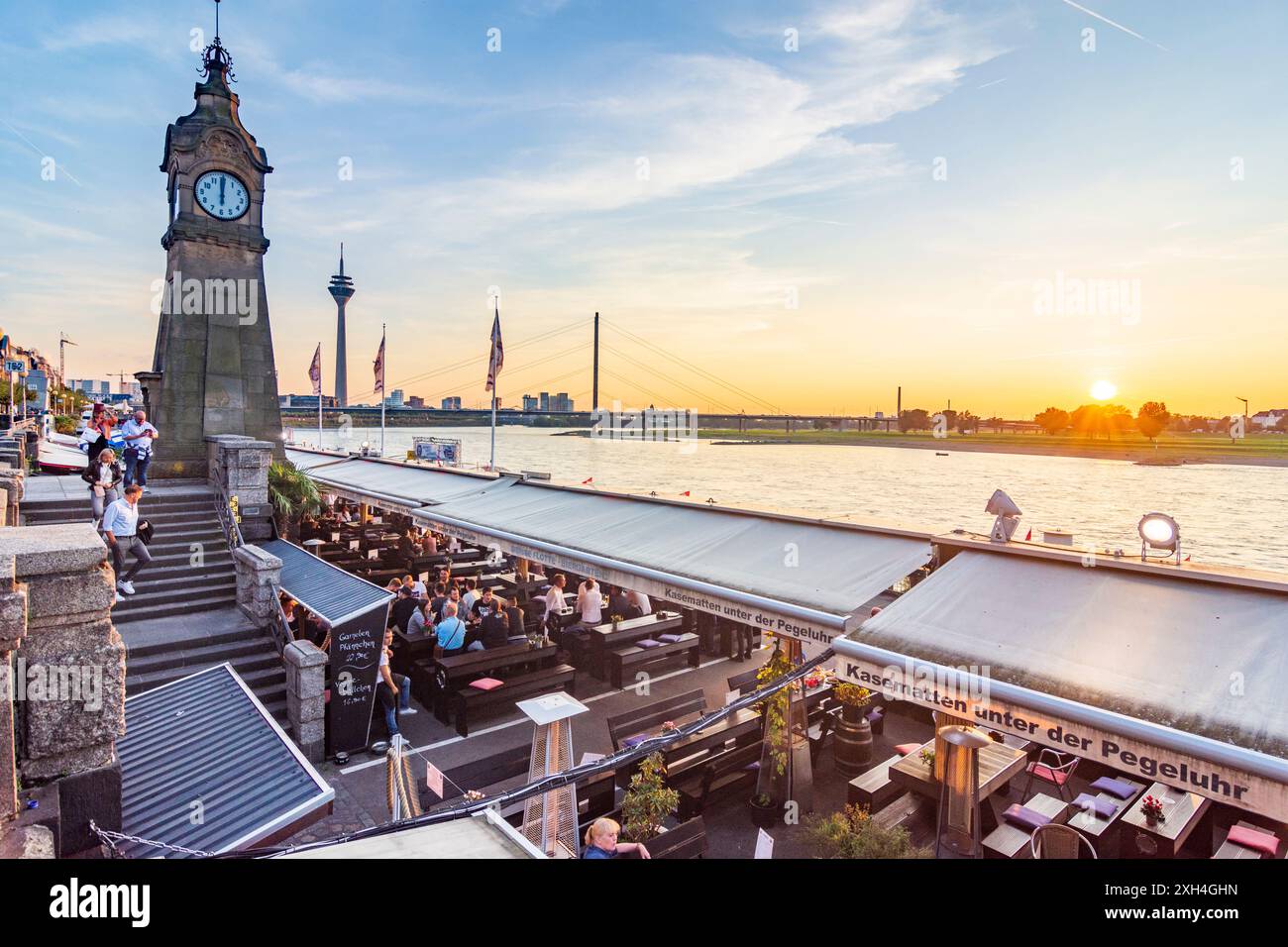 Düsseldorf: Alter Pegelturm (torre a scartamento antico) con orologio standard sulla passeggiata sul Reno (Rheinuferpromenade), fiume Reno, ristorante all'aperto, bridg Foto Stock