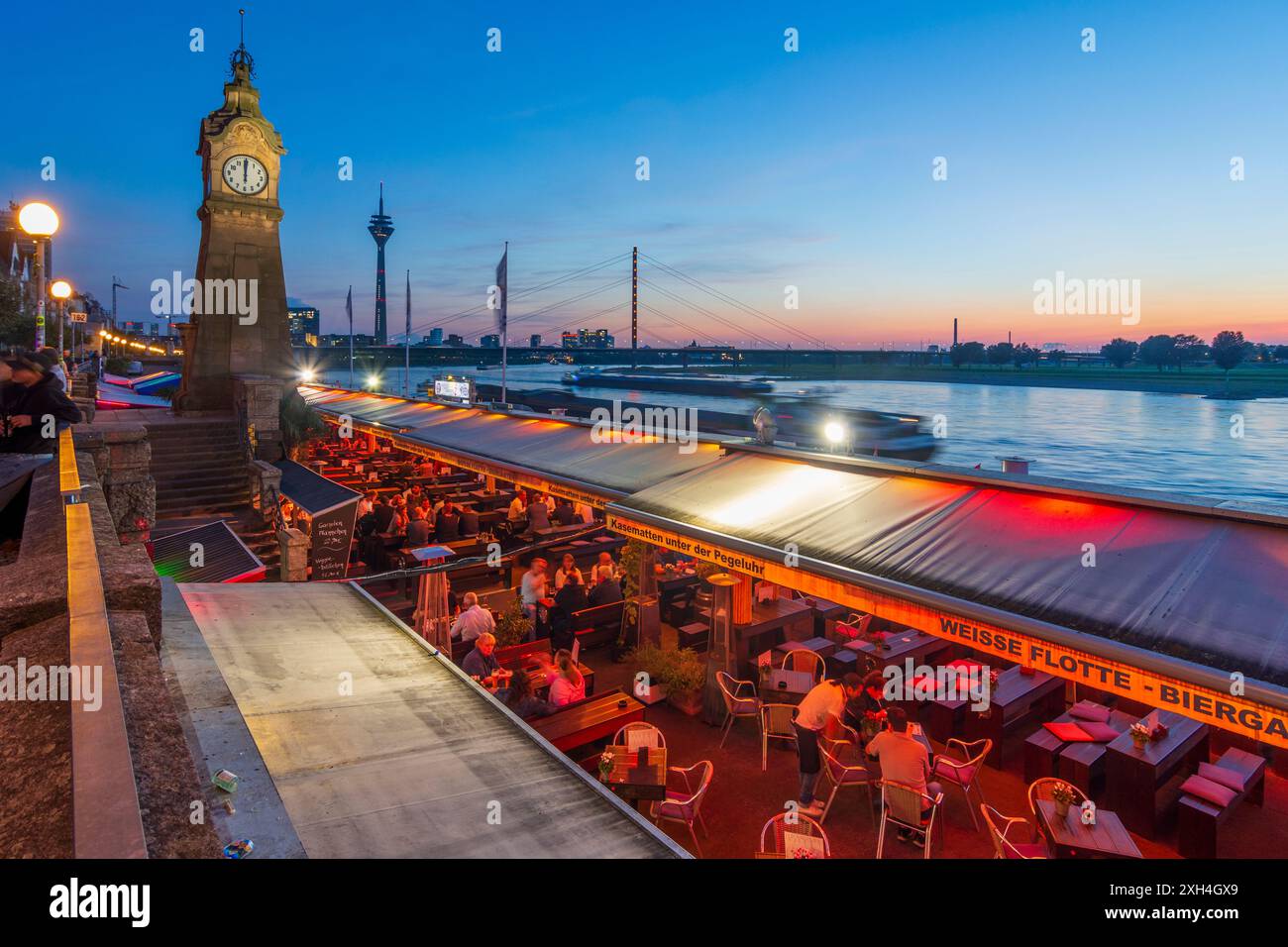 Düsseldorf: Alter Pegelturm (torre a scartamento antico) con orologio standard sulla passeggiata sul Reno (Rheinuferpromenade), fiume Reno, ristorante all'aperto, bridg Foto Stock