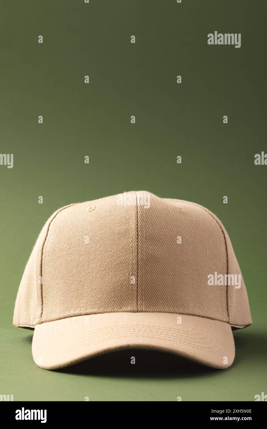 Un cappellino da baseball beige è posizionato su uno sfondo verde, con spazio per le copie. Il colore neutro e il design classico lo rendono un accessorio versatile Foto Stock