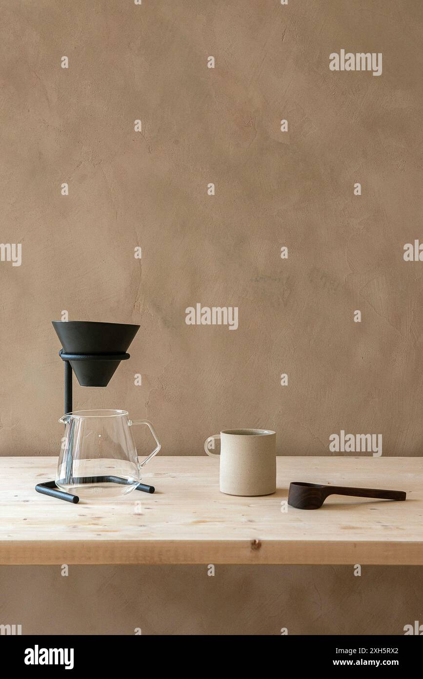 La macchina da caffè si trova su un tavolo in legno minimalista. Concetto minimalista. Foto Stock