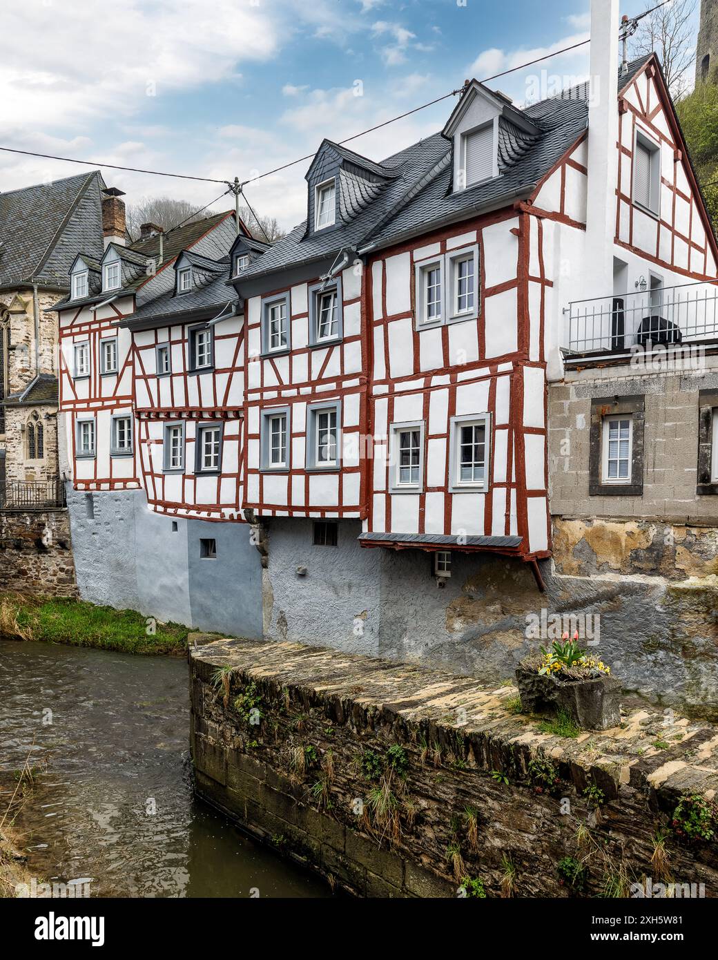Affascinanti case in legno lungo un fiume con un castello medievale su una collina nebbiosa a Monreal, Germania. Foto Stock