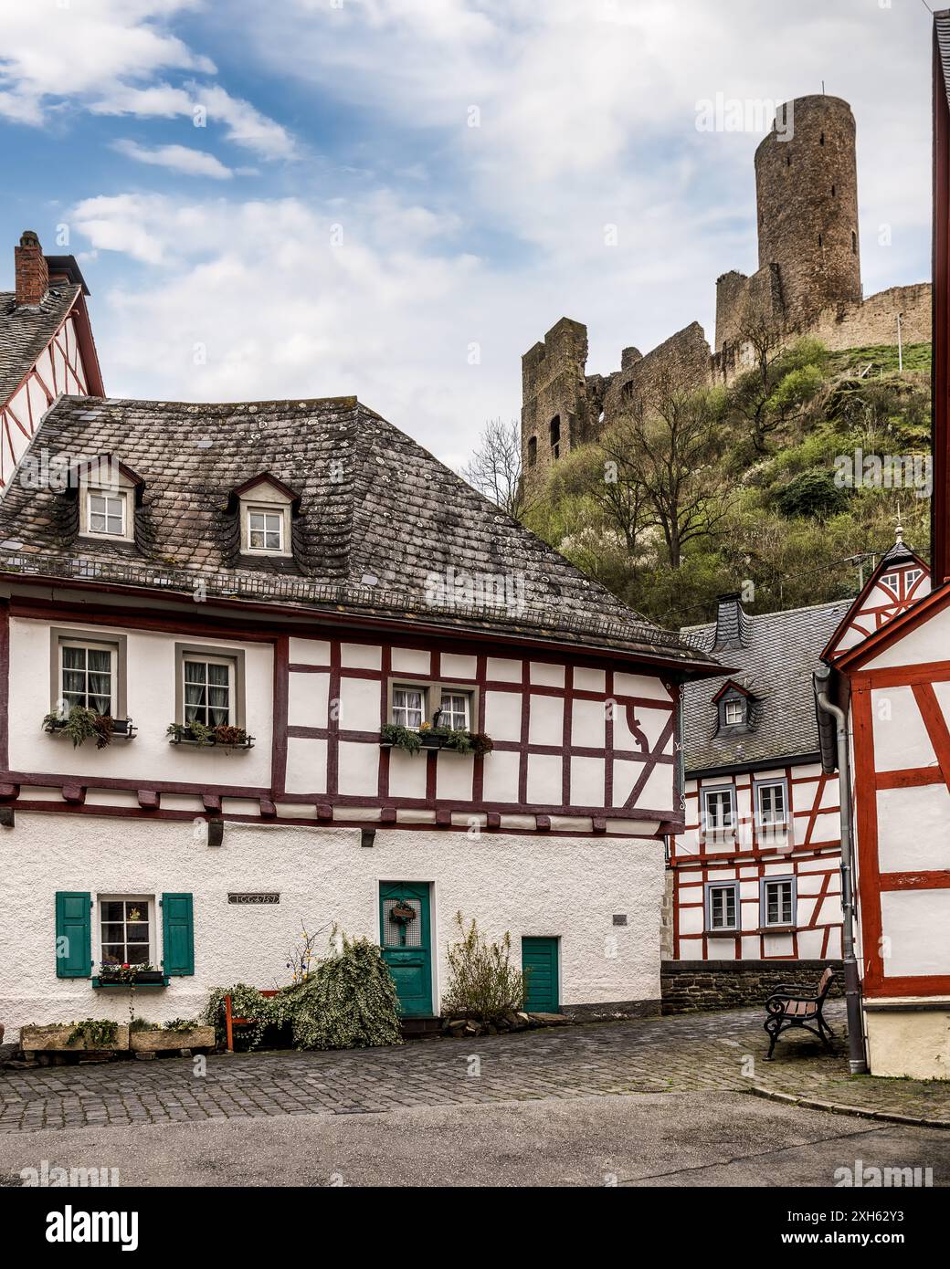 Affascinanti case in legno lungo un fiume con un castello medievale su una collina nebbiosa a Monreal, Germania. Foto Stock
