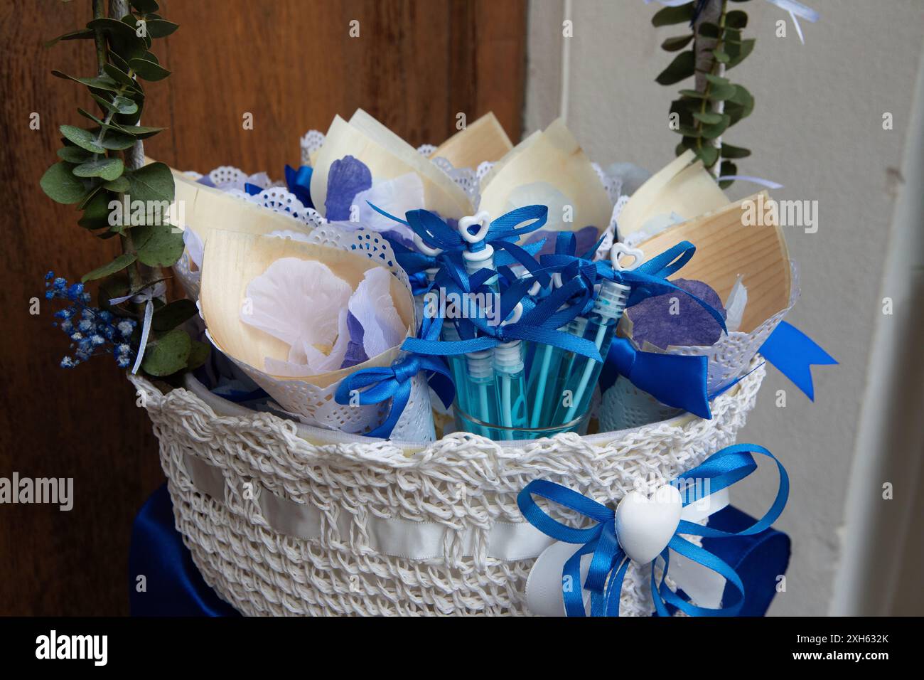 Cestino di vimini bianco decorato con nastri blu contenenti coni di riso e bolle di sapone per una cerimonia nuziale Foto Stock