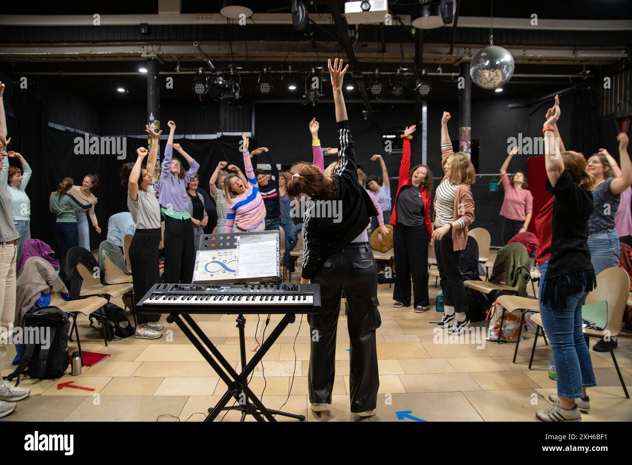 2 luglio 2024, Baviera, Norimberga: Le donne si allungano durante una prova del coro per allentare i loro corpi per il canto successivo. Con un repertorio moderno che va oltre la solita letteratura corale, le Desirenen stanno godendo di grande successo a Norimberga e stanno attirando sempre più cantanti femminili. Altri due cori femminili sono già emersi da quelli interessati al progetto coro fondato nel 2013. Foto: Pia Bayer/dpa Foto Stock