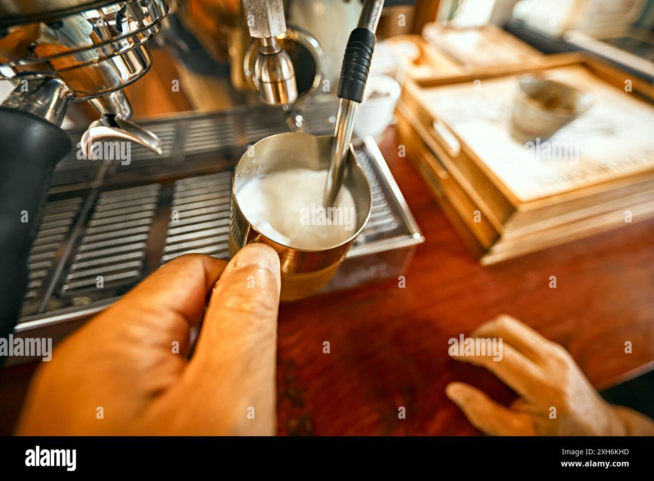 Primo piano, il barista prepara la schiuma di latte caldo su una macchina per il caffè Foto Stock