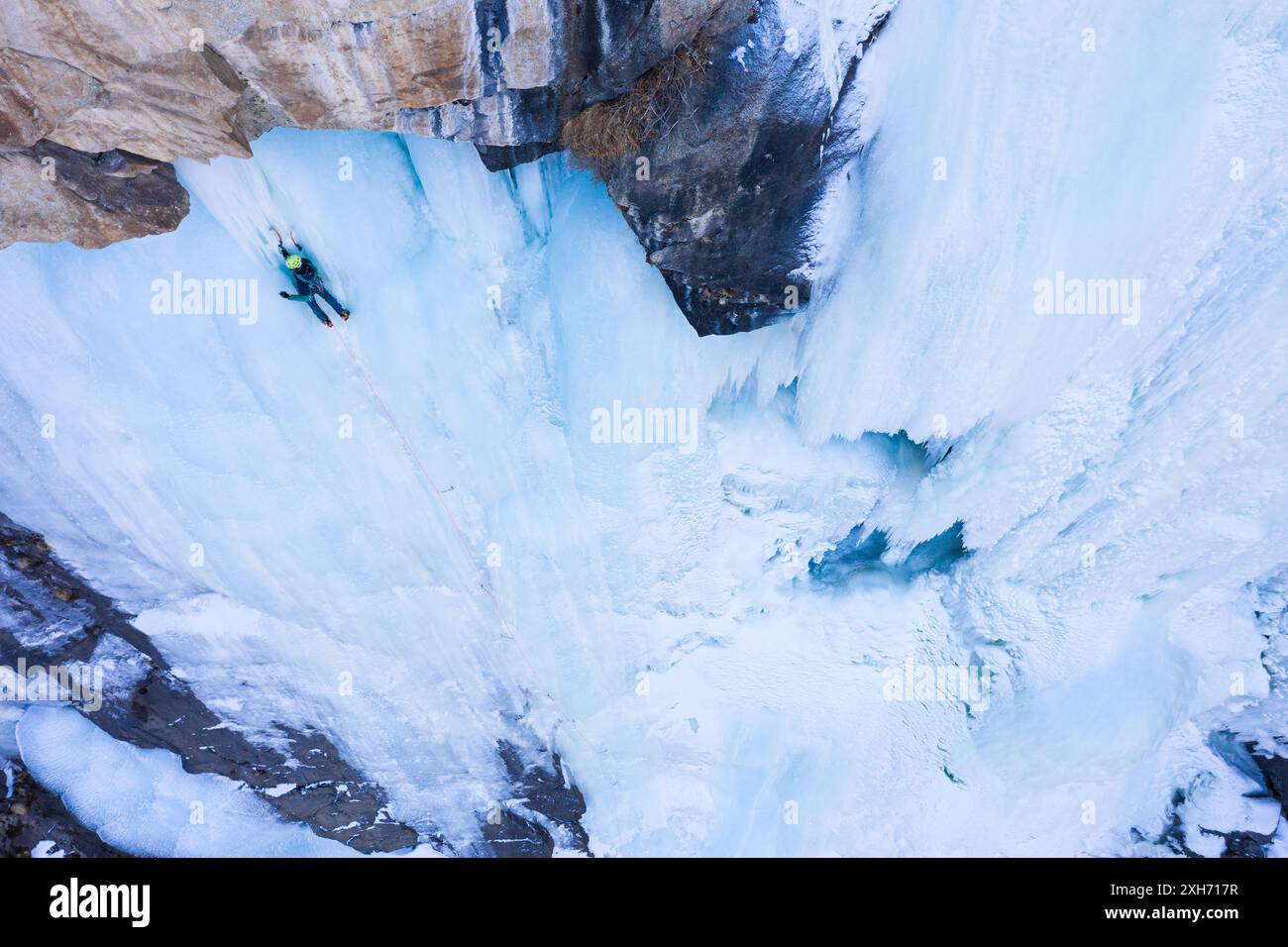 L'uomo sta guidando su Ice. Arrampicata su ghiaccio sulla cascata ghiacciata, vista aerea. Valle di Barskoon, Kirghizistan Foto Stock