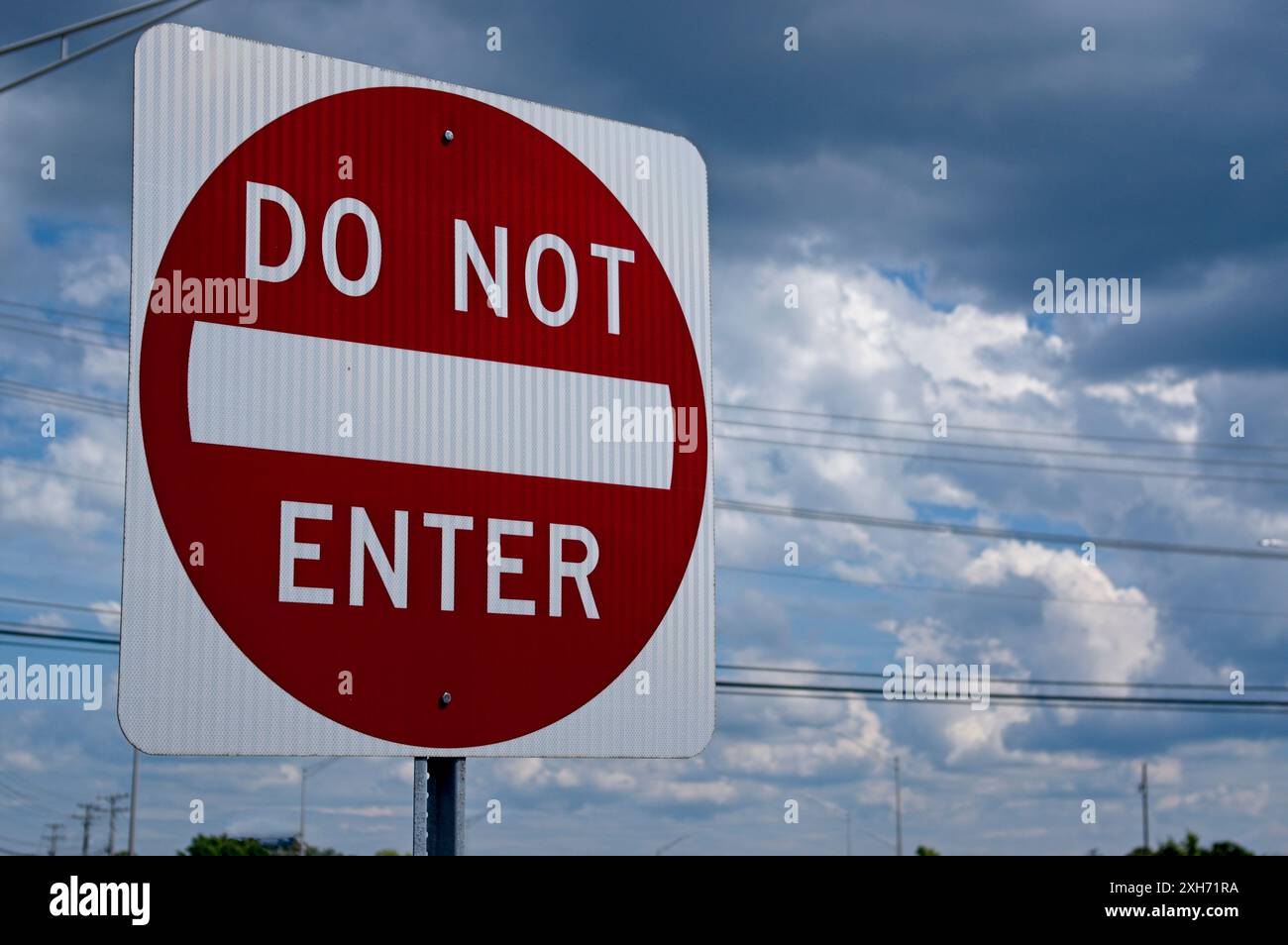 Un segno "non entrare" rosso e bianco su uno sfondo nuvoloso, con linee elettriche Foto Stock