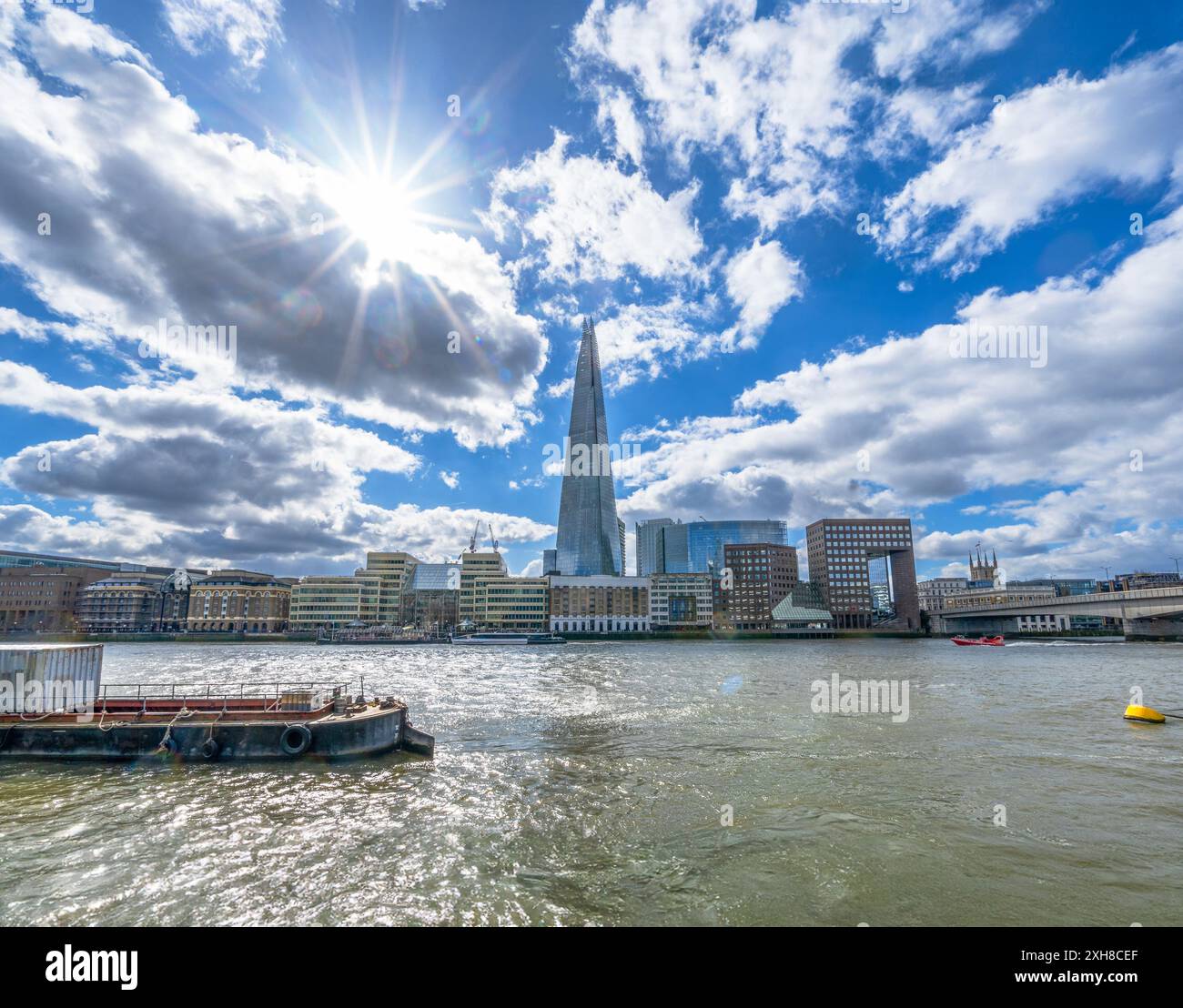 Vista del Tamigi a Londra con il grattacielo Shard sullo sfondo retroilluminato con luci delle lenti e raggi del sole e imbarcazioni da diporto in barca a vela e a m Foto Stock