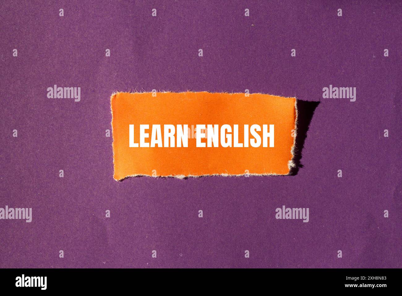 Impara il messaggio in inglese scritto su un pezzo di carta arancione strappato con sfondo viola. Simbolo Impara l'inglese concettuale. Copia spazio. Foto Stock