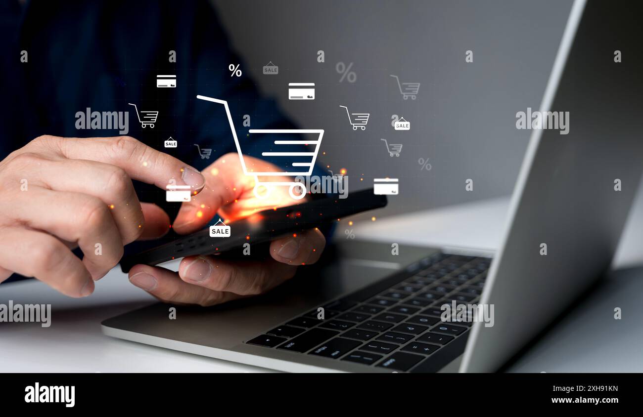 Concetto di e-commerce aziendale. Persona che utilizza smartphone e laptop con l'icona del carrello online sullo schermo virtuale. acquisto online, negozio di e-commerce, onlin Foto Stock
