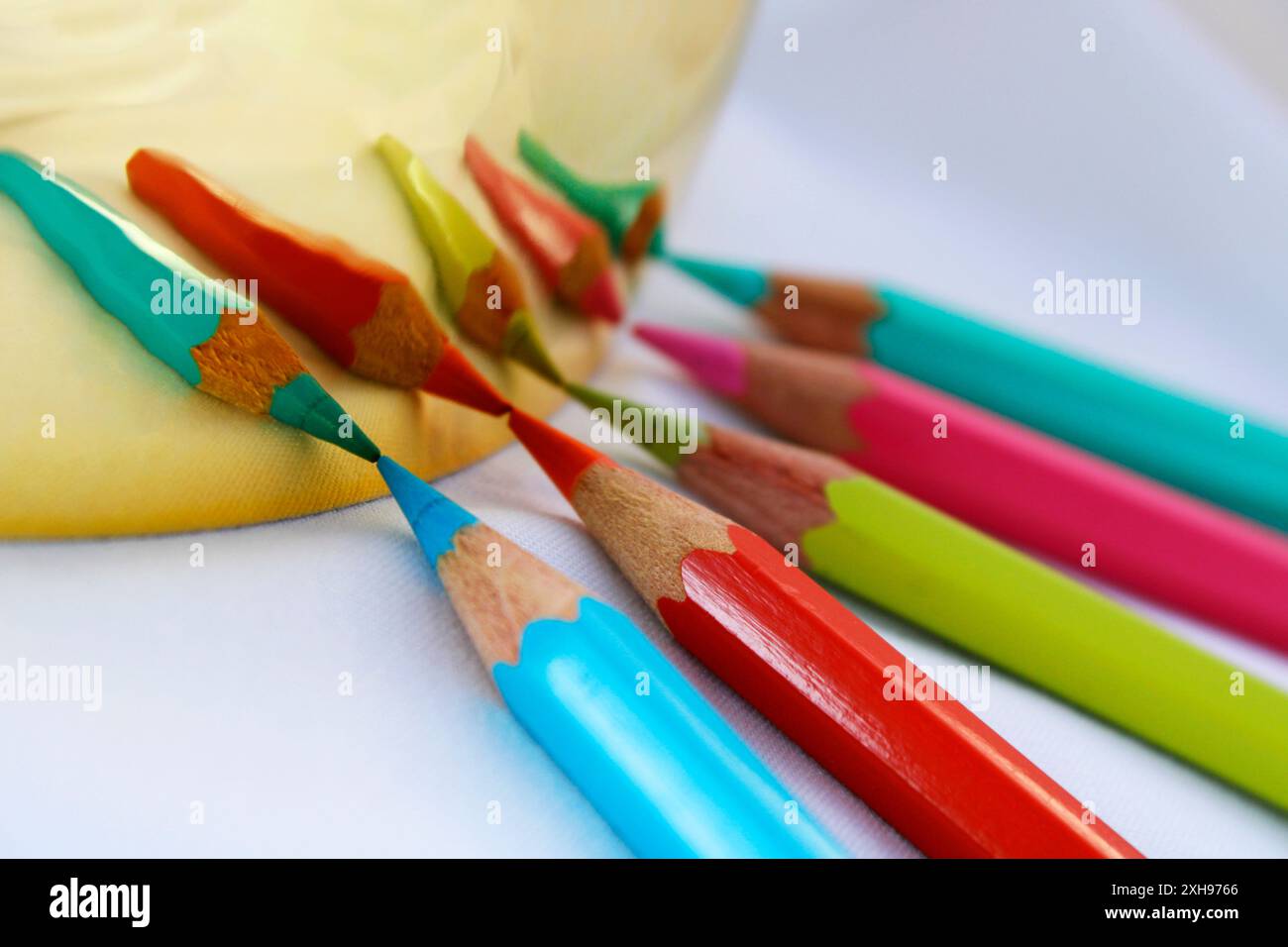 Matite di diversi colori riflesse su una superficie dorata Foto Stock