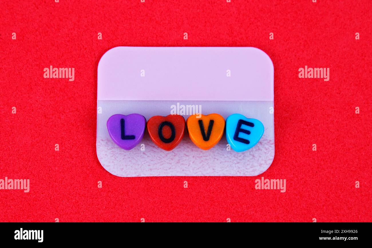 Cuori colorati con la parola amore su una nota adesiva Foto Stock