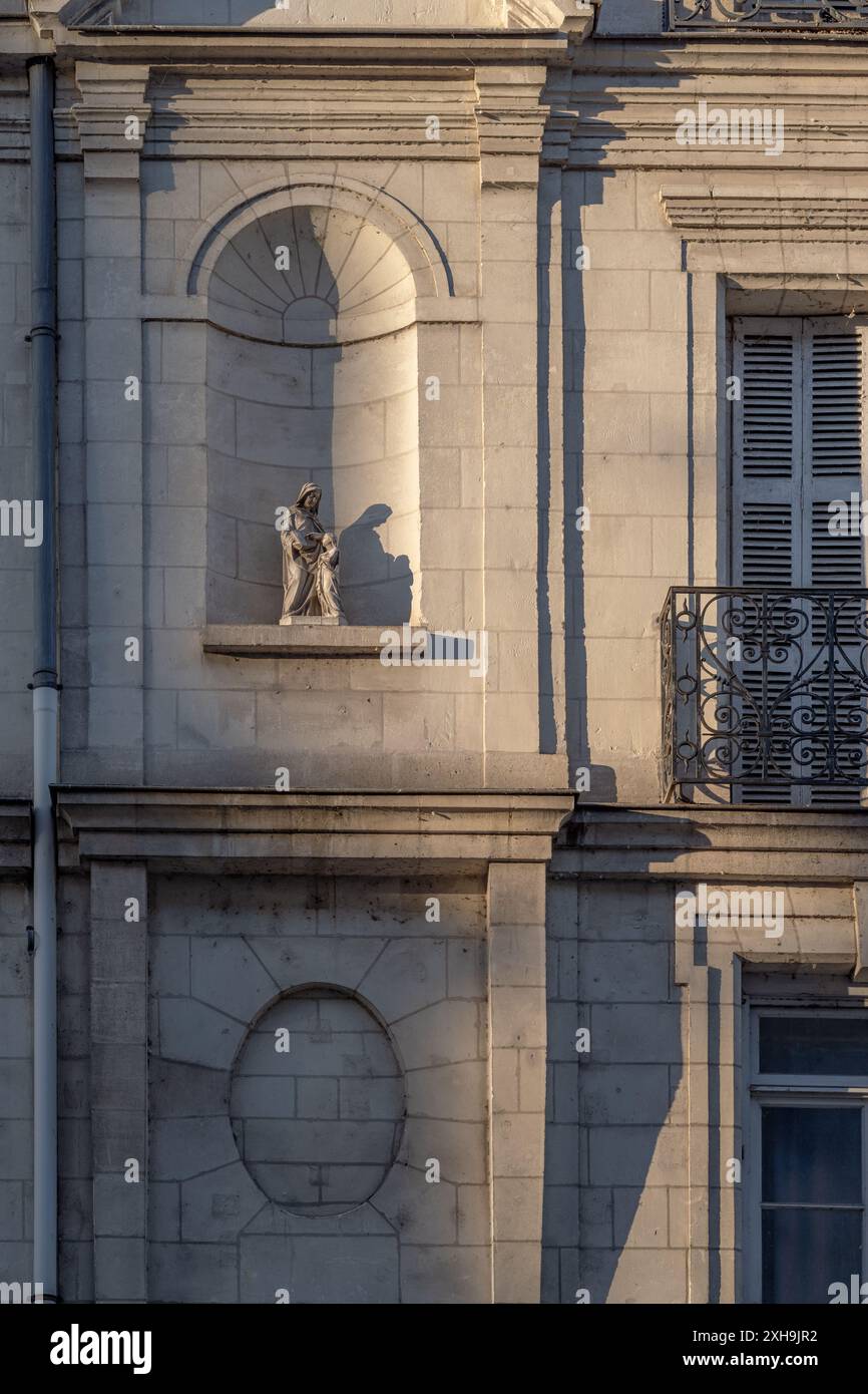 Una scultura di una Vergine Maria adagiata su una facciata di un edificio in Francia. Scattato durante una soleggiata serata estiva con motivi d'ombra e senza persone. Foto Stock