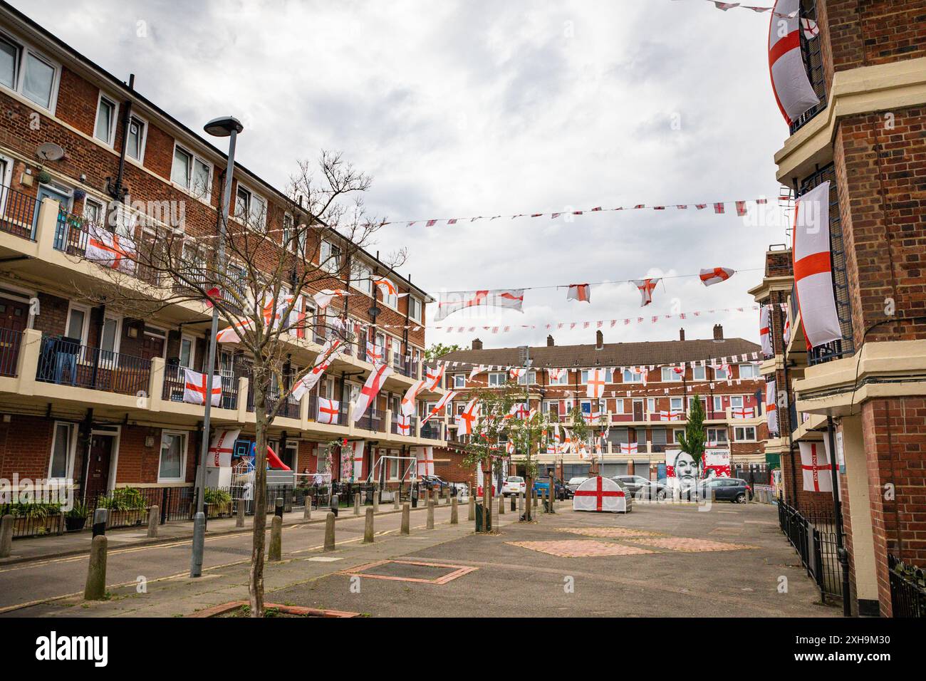 Bermondsey, Londra, 12 luglio 2024. La tenuta Kirby di Bermondsey, nota per le sue colorate bandiere per le partite di calcio dell'Inghilterra, è ancora una volta decorata con diverse centinaia di bandiere in tutta la tenuta patriottica, così come il murale recentemente inaugurato di Eberechi Eze e altri pittoreschi murales nei grouds, in vista della finale di domenica tra Inghilterra e Spagna dei Campionati europei di calcio. Crediti: Imageplotter/Alamy Live News Foto Stock