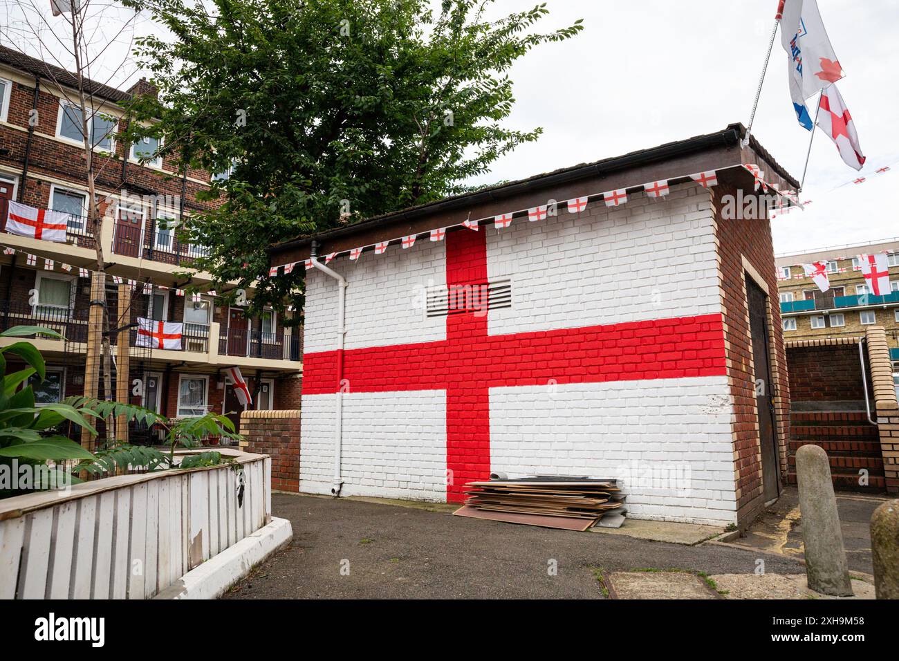 Bermondsey, Londra, 12 luglio 2024. Anche il deposito ha subito un restyling, con una bandiera inglese. Kirby Estate a Bermondsey, conosciuta per le sue colorate bandiere per le partite di calcio dell'Inghilterra, è ancora una volta addobbata in diverse centinaia di bandiere in tutta la tenuta patriottica, così come il murale recentemente inaugurato di Eberechi Eze e altri pittoreschi murales nei grouds, in vista della finale di domenica tra Inghilterra e Spagna dei Campionati europei di calcio. Crediti: Imageplotter/Alamy Live News Foto Stock