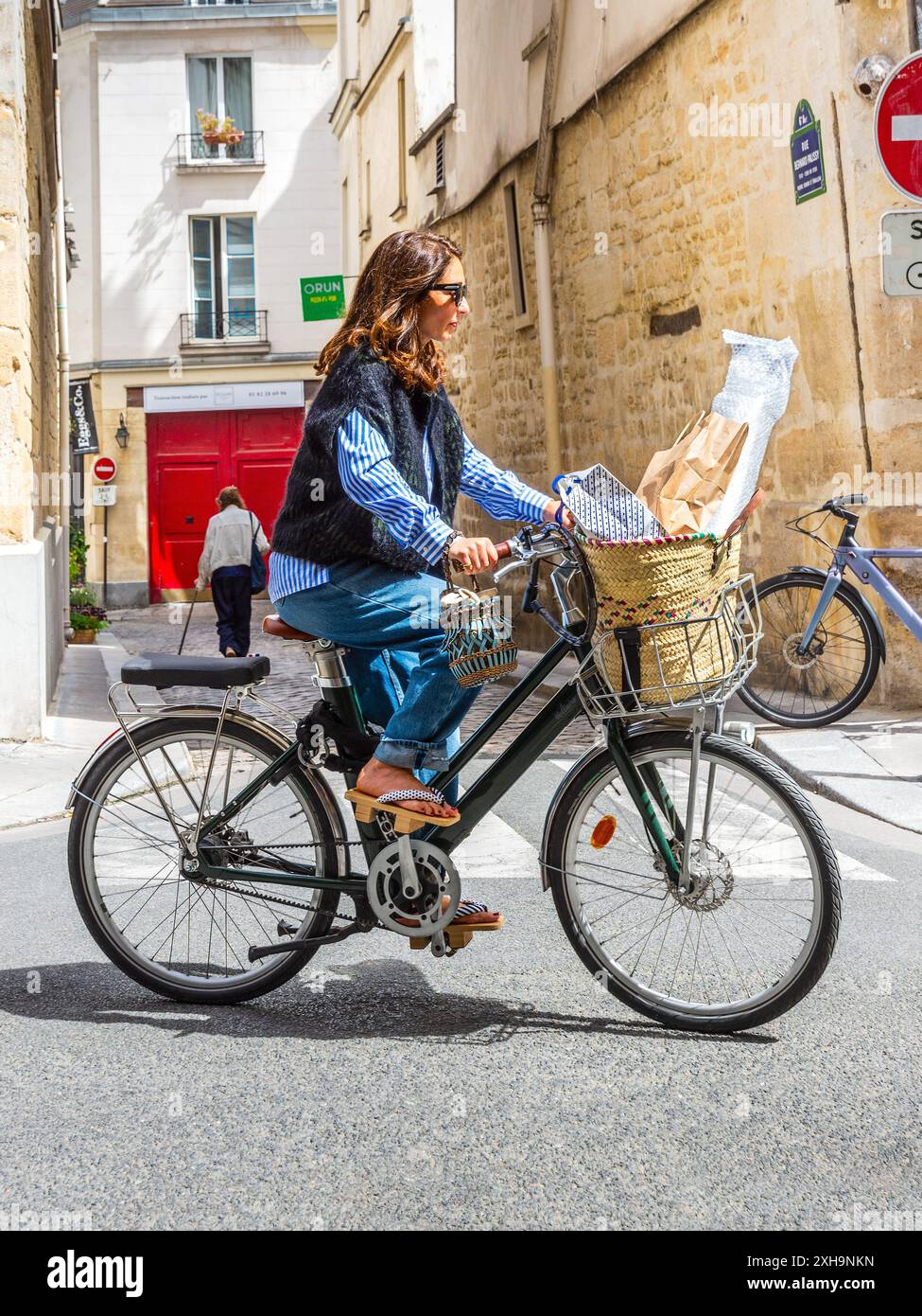Giovane donna alla moda su una bicicletta elettrica "Voltaire Bellecour" in Rue du Dragon, Parigi 75006, Francia. Foto Stock