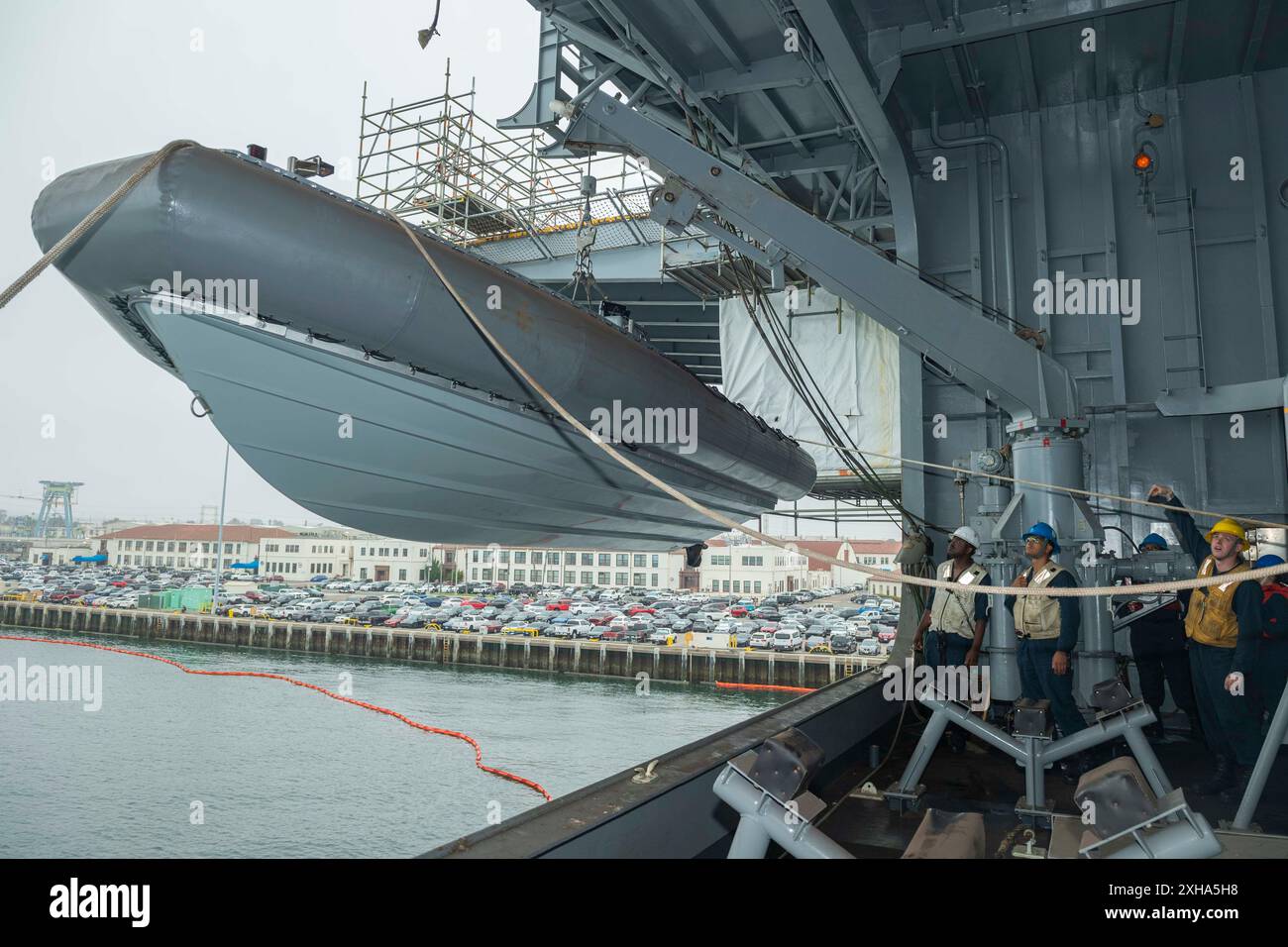 Boatswain's Mate 2nd Class Elijah Parra, a destra, assegnata alla nave d'assalto anfibia USS Essex (LHD 2) dirige l'operatore per il davit a braccio girevole ad abbassare un gommone a scafo rigido (RIB) di 7 m durante le operazioni in piccole imbarcazioni a bordo dell'Essex, 10 luglio 2024. Essex è stato portato a San Diego, conducendo un periodo di manutenzione per aggiornare e rinnovare molti sistemi chiave a bordo. (Foto della Marina degli Stati Uniti di Richard E. Anglin, specialista di comunicazione di massa di seconda classe) Foto Stock