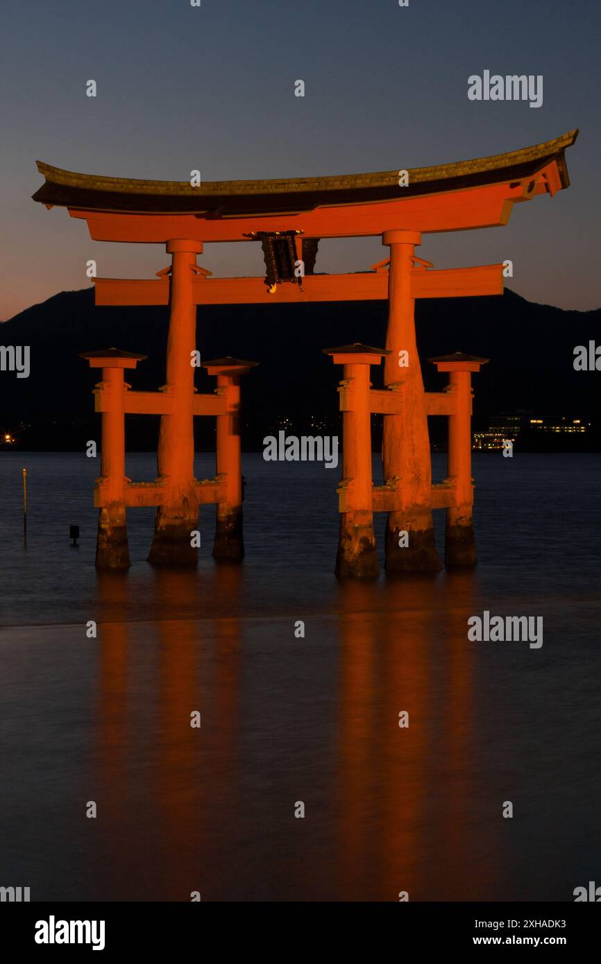 La famosa porta torii galleggiante al Santuario Itsukushima sull'Isola di Miyajima illuminata al crepuscolo. Hiroshima, Giappone Foto Stock