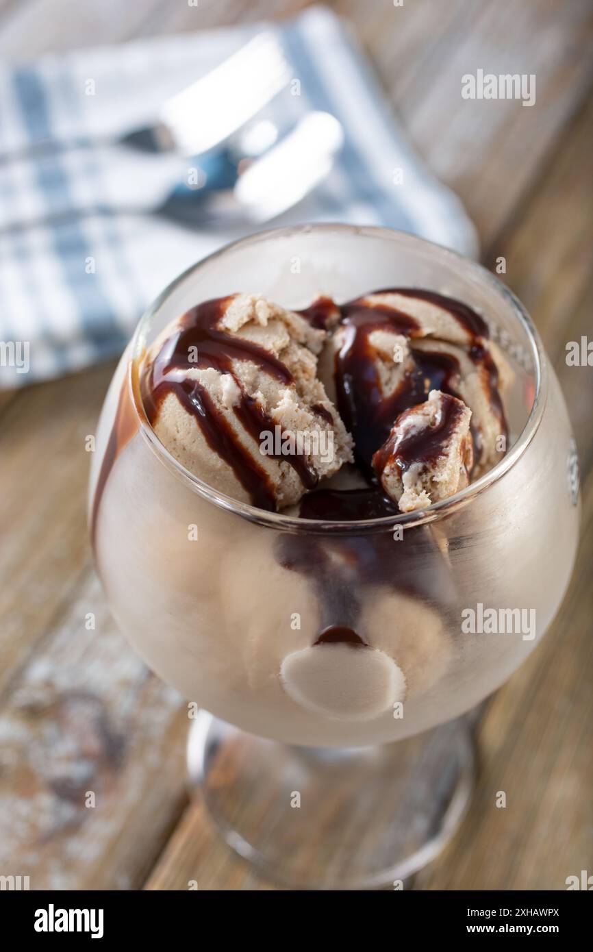 Vista ravvicinata di un bicchiere di gelato al cioccolato, con sciroppo al cioccolato. Foto Stock