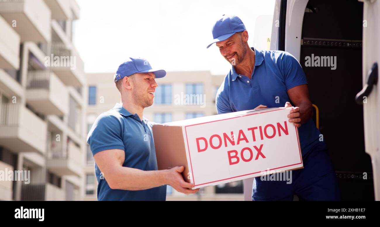 Programma di sensibilizzazione della comunità: I volontari Mover scaricano la scatola delle donazioni da Truck, il lavoratore filantropico aiuta i senzatetto con Canned Food. Foto Stock
