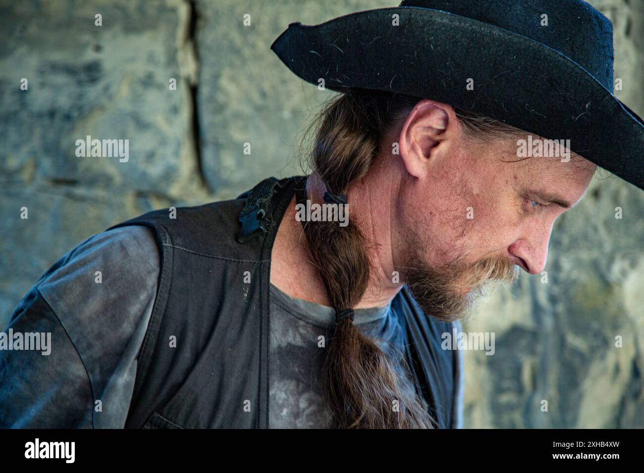 Emotional Ritratto di un uomo in abiti da viaggio e un cappello sullo sfondo di un muro di una fortezza. Archeologia. Studio. Viaggio. Foto Stock