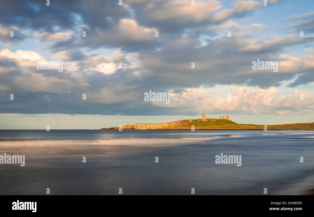 Ora d'oro serale per ammirare le rovine del castello di Dunstanburgh dalla baia di Embleton sulla costa del Northumberland, Inghilterra nord-orientale, Regno Unito Foto Stock