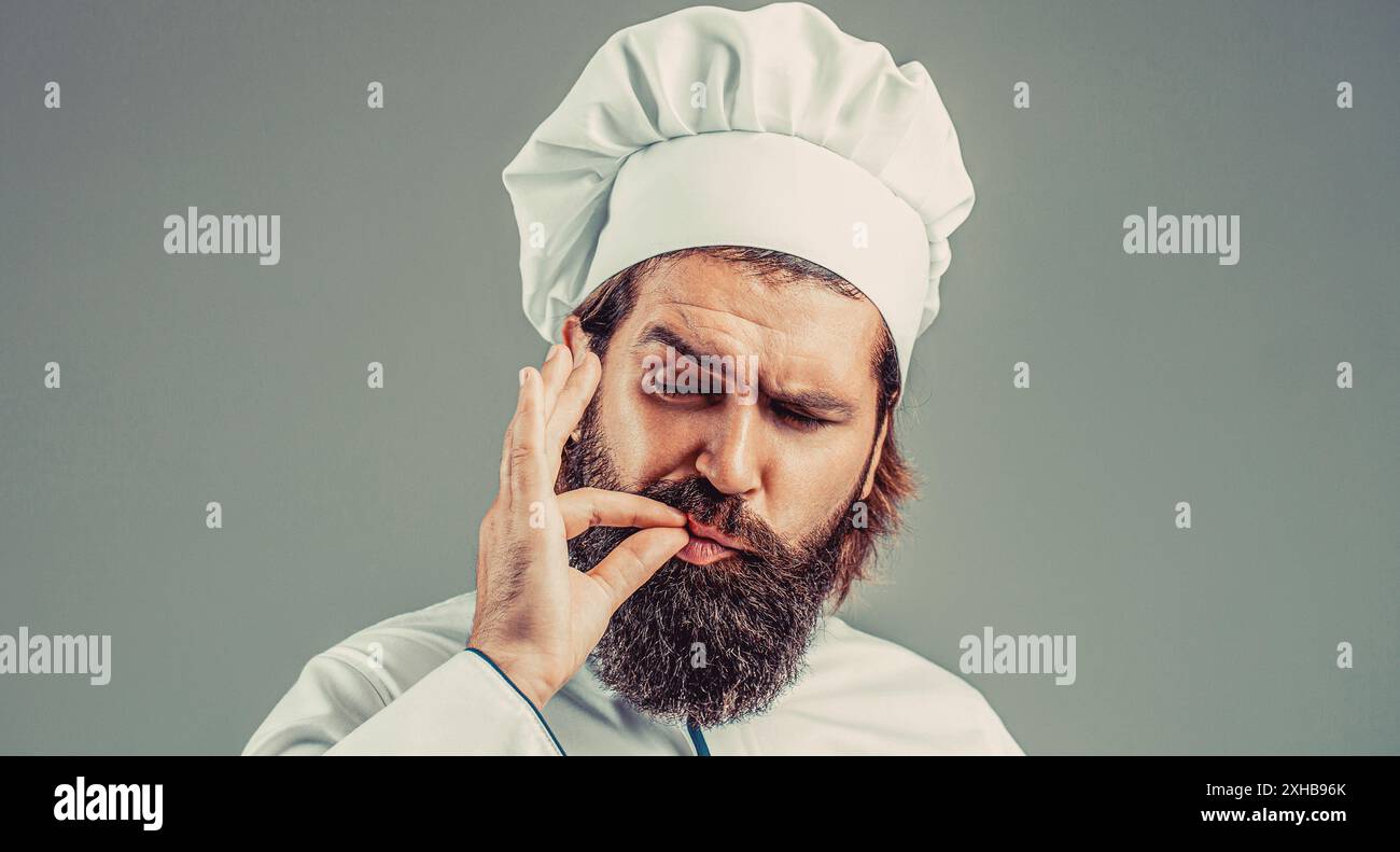 Lo chef hipster fiducioso con barba e baffi in uniforme da cuoco mostra un sospiro di eccellenza, eccellente. Ritratto di un cuoco felice. Cappello da cucina. Barbuti Foto Stock
