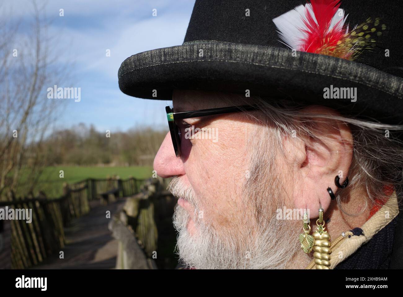 Profilo di un uomo del 71 attento alla moda con barba, occhiali, cappello e orecchini Foto Stock