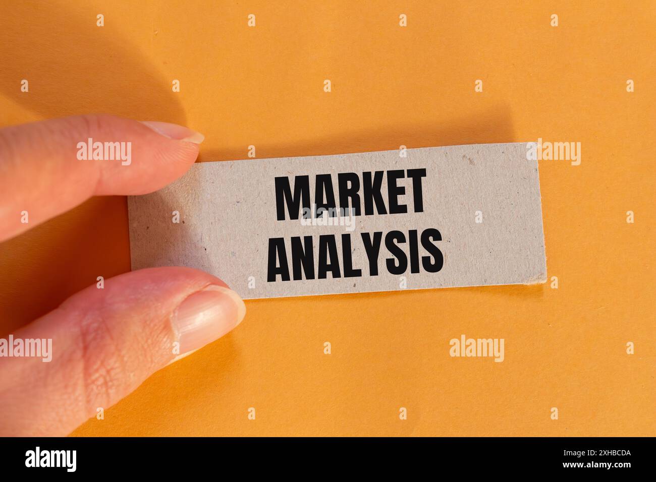Messaggio di analisi del mercato scritto su un foglio di carta strappato con sfondo arancione. Simbolo dell'analisi concettuale di mercato. Copia spazio. Foto Stock