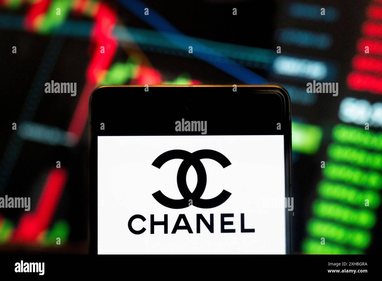 Cina. 21 giugno 2024. In questa illustrazione fotografica, il logo Chanel del marchio di bellezza cosmetica multinazionale Fench è stato visualizzato su uno smartphone con un grafico dell'indice di borsa economica sullo sfondo. Credito: SOPA Images Limited/Alamy Live News Foto Stock